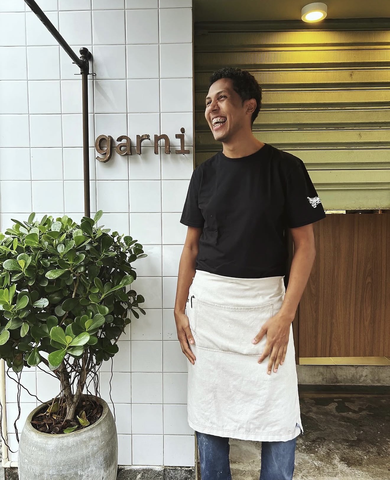 Kaique Sérgio sorrindo de avental em frente ao Garni Lab